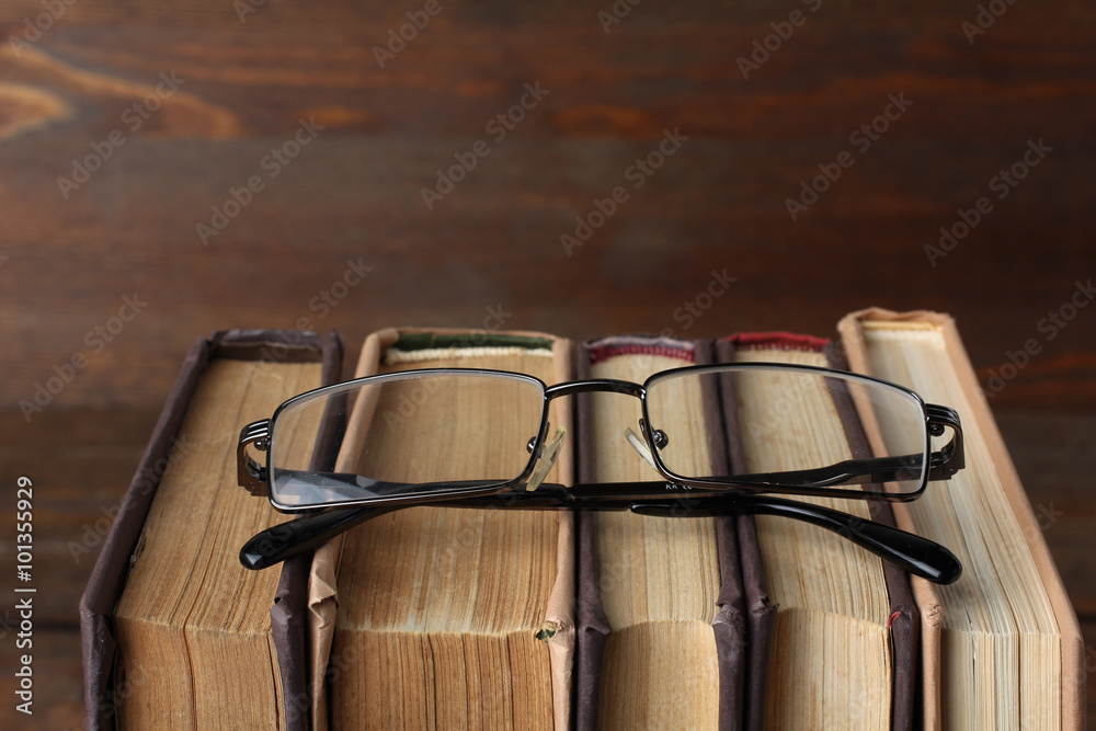 the book is in color the cover are stacked near glasses on wooden table the book is in color the cover are stacked near glasses on wooden table