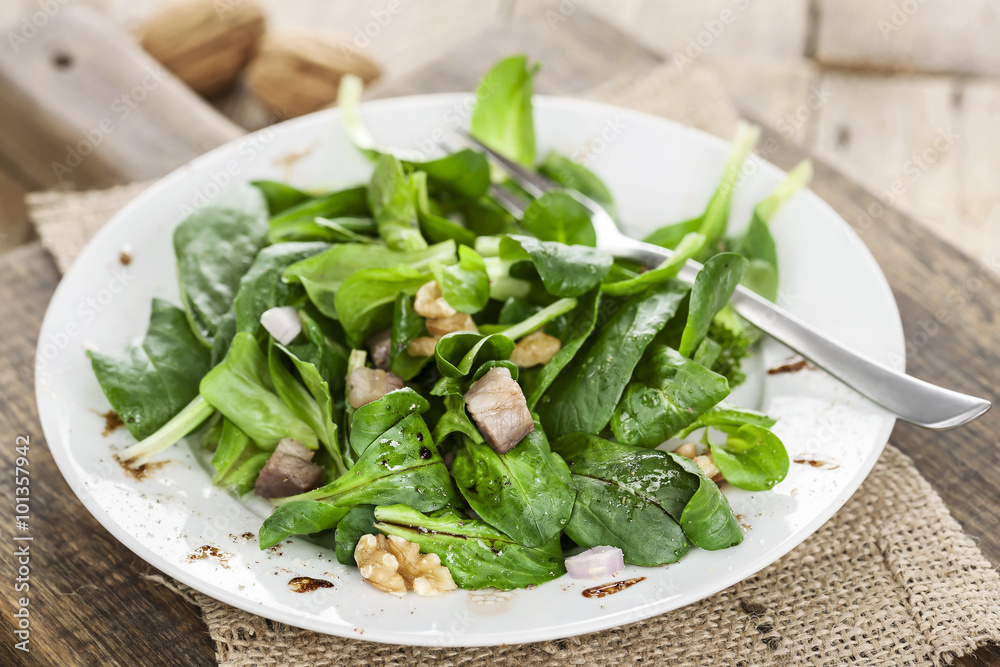 Frisch angemachter Feldsalat mit Speck und Nüssen auf einem Teller Frisch angemachter Feldsalat mit Speck und Nüssen auf einem Teller