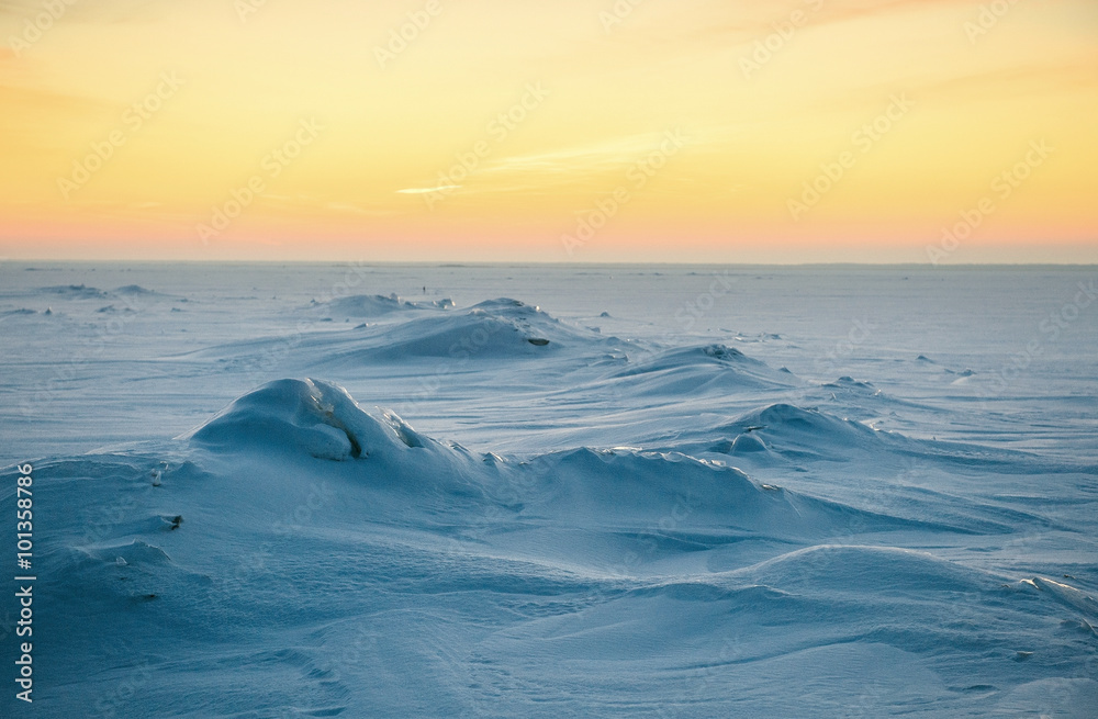 A beautiful wintry sunset. An image of a sun going down behind the horizon and it is making a unusual color to the snow. The lake is covered of ice and snow. A beautiful wintry sunset. An image of a sun going down behind the horizon and it is making a unusual color to the snow. The lake is covered of ice and snow.
