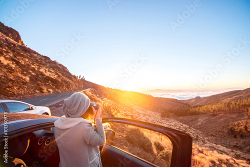 Woman photographing landscape standing near the car