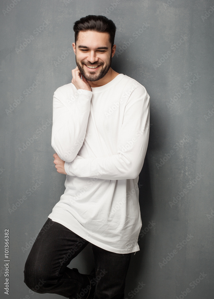 sexy fashion man model in white sweater, jeans and boots smiling