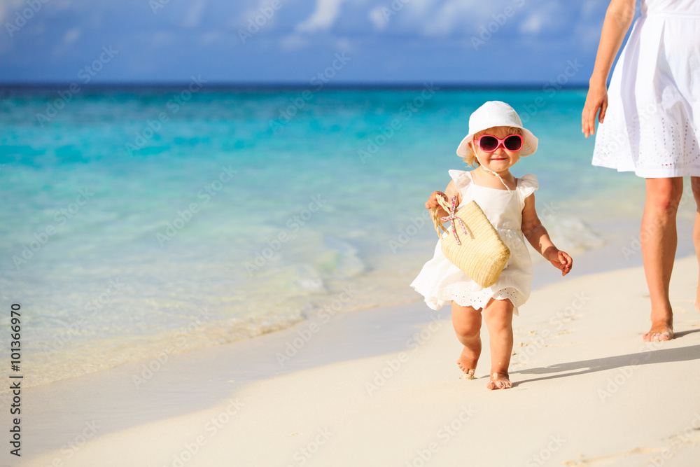 cute little girl walking on the beach with mother cute little girl walking on the beach with mother