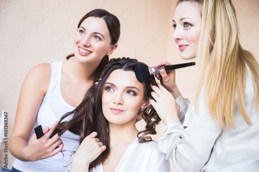 Stylist and makeup artist preparing bride before the wedding in a morning Stylist and makeup artist preparing bride before the wedding in a morning