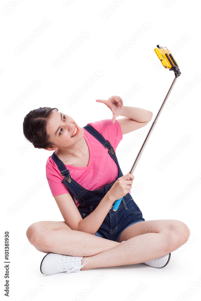 Young woman taking picture with smartphone selfie stick and sitting on the floor. Young woman taking picture with smartphone selfie stick and sitting on the floor.