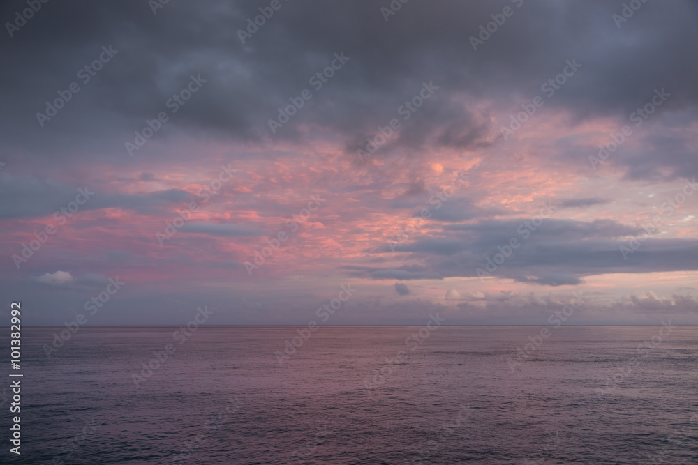 Blue hour with clouds of different colors. High clouds are orange and red, low clouds greenish blue.