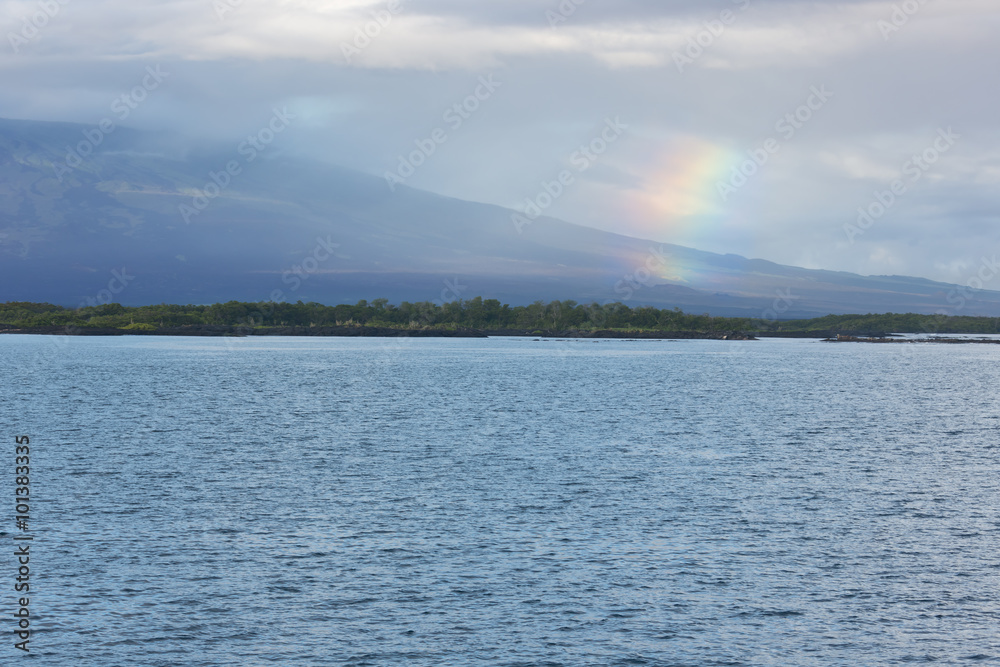 Rainbow over Isabela with shield volcano. Rain over land reduces the contrast.