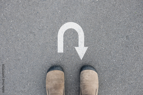 Fotografi Brown suede shoes standing in front of U turn sign