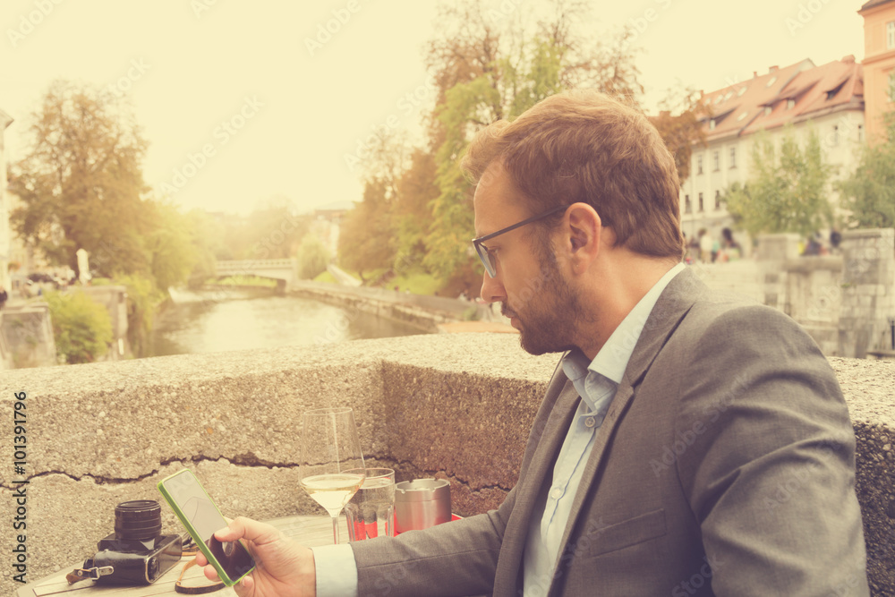 Young man drinking wine and using cellphone outdoors. Young man drinking wine and using cellphone outdoors.
