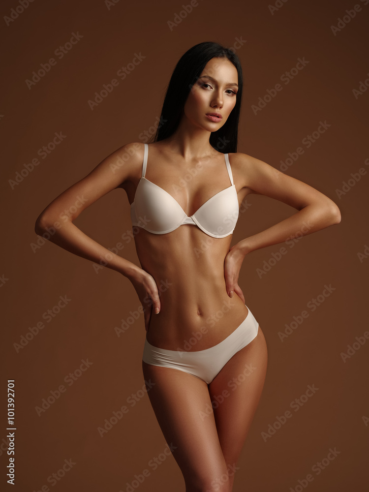 Beautiful very slim girl with black straight hair is posing in the white  basic seamless underwear collection in the studio Stock Photo | Adobe Stock