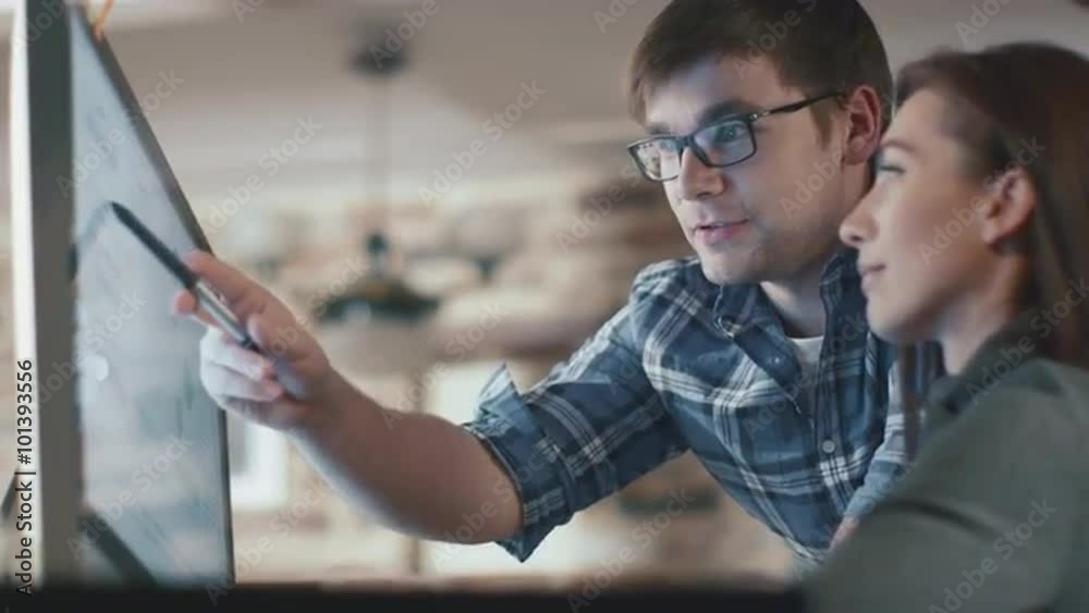 Young man and woman are working on a computer in a loft while discussing a project. Shot on RED Cinema Camera.