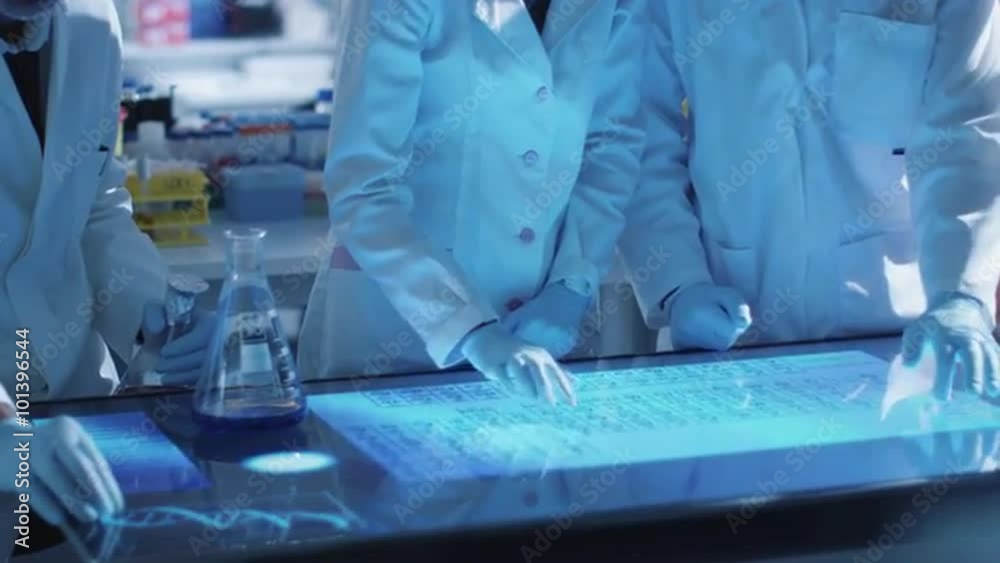 Team of scientists are working on a digital touch screen in a laboratory. Shot on RED Cinema Camera. Team of scientists are working on a digital touch screen in a laboratory. Shot on RED Cinema Camera.