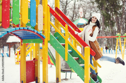 Street photo of beautiful happy woman on the playground. Model wearing classic stylish winter clothes. Full body portrait