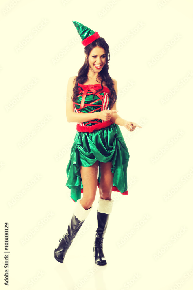 Full length woman wearing elf clothes pointing to the right