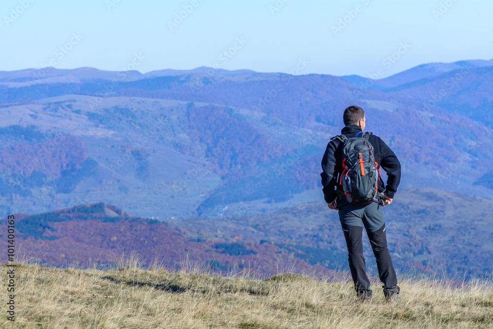 Young tourist man standing on mountain.  Happy young tourist man