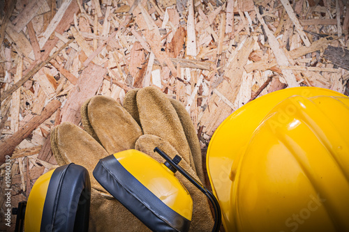 Safety leather gloves building helmet earmuffs on chipboard photo