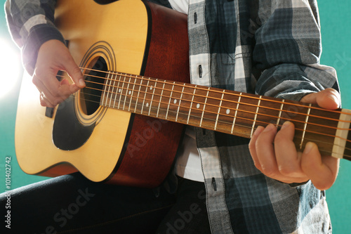 Musician plays guitar on blue background, close up