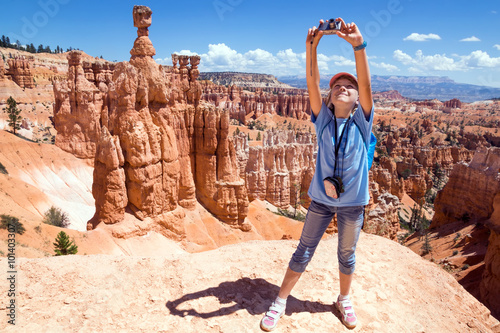 Fototapet Girl photographs on the camera mountain landscape. Bryce Canyon