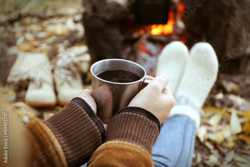 Woman sitting beside the fire with a cup of coffee