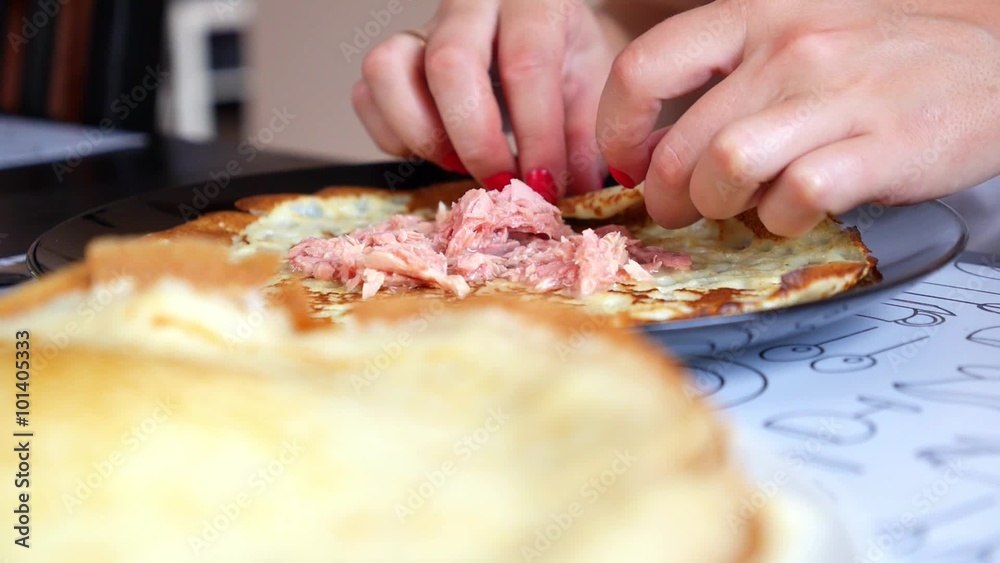 Female Hands Making Pancake Roll with Tuna. Closeup. Female Hands Making Pancake Roll with Tuna. Closeup.