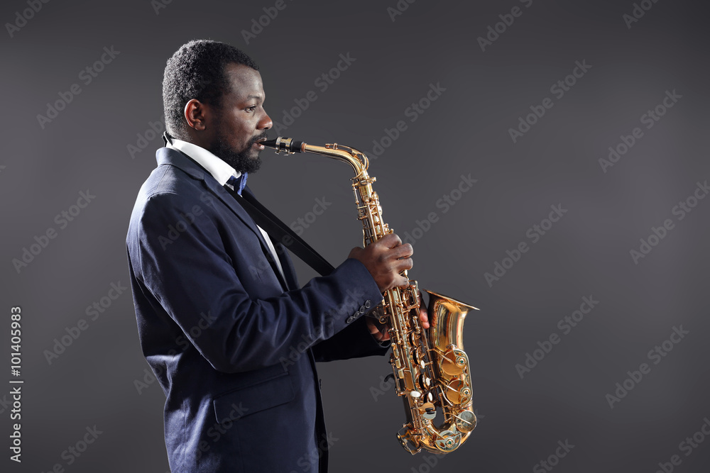Fototapeta premium African American jazz musician playing the saxophone on grey background