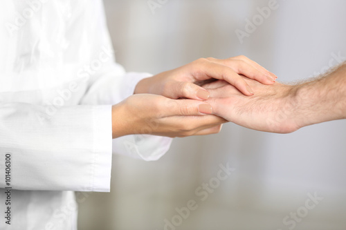 Hand of medical doctor carefully holding patient's hands