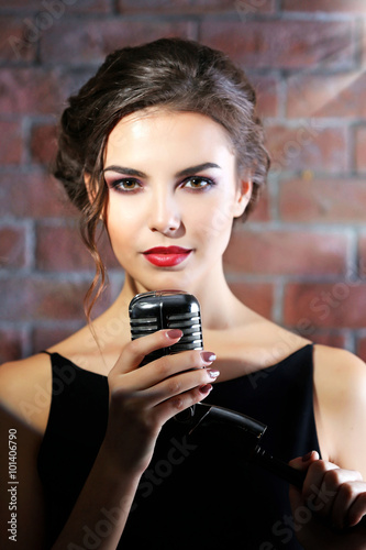 Portrait of attractive singing woman on brick wall background, close up