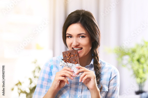 Portrait of beautiful young brunette with chocolate in the room   close up
