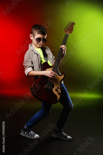 Little boy playing guitar on a bright background