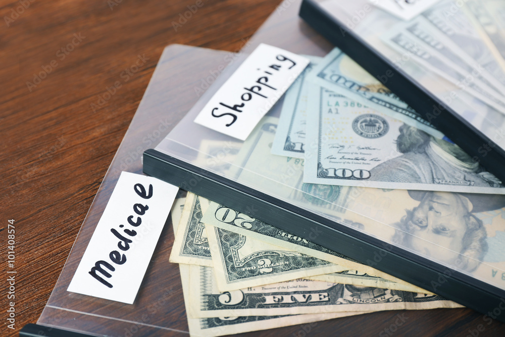 Distribution of money, financial planning, dollars in envelopes, on wooden table background Distribution of money, financial planning, dollars in envelopes, on wooden table background