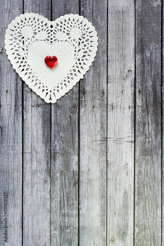 heart doily with red heart bead on top of wood table