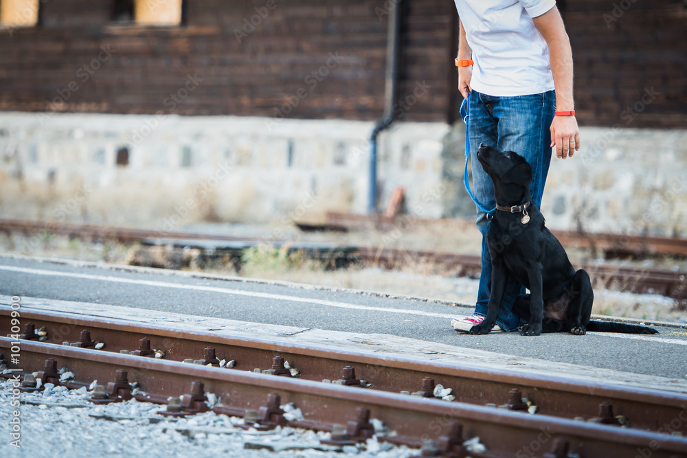 Owner and his black labrador waiting for the train Owner and his black labrador waiting for the train