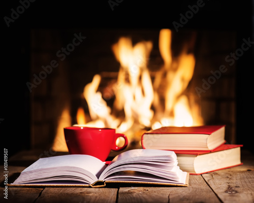 Red cup of coffee or tea and old books on wooden table near fir