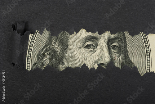 Benjamin Franklin macro peeking through torn black paper