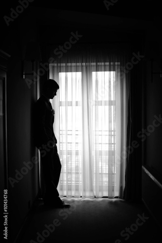 the figure of a man standing in the dark hallway groom