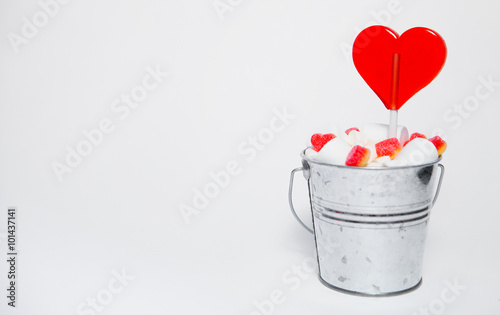 Lollipop heart shaped in Small bucket with sweets on white backg