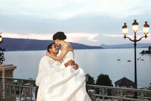Happy couple husband and wife hugging at balcony in evening near