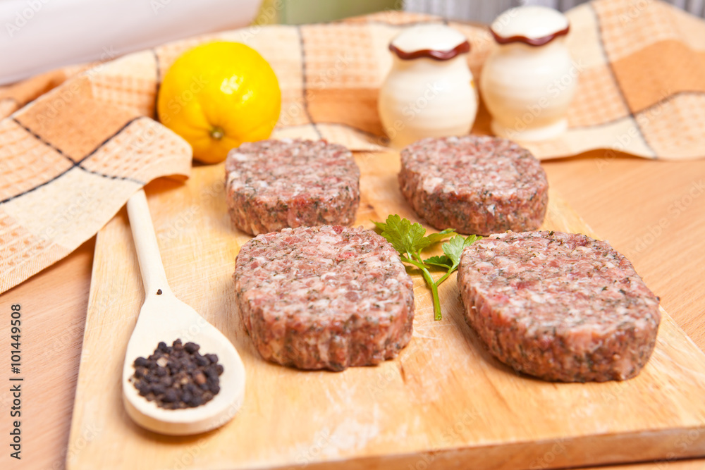 raw patties with spices on a cutting board raw patties with spices on a cutting board