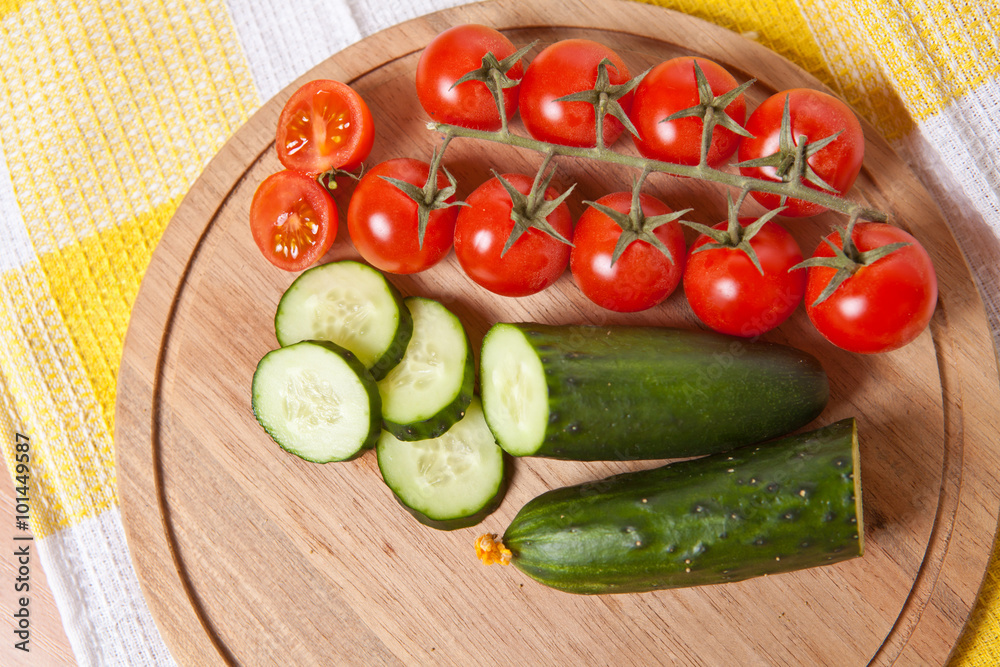 cherry tomatoes and cucumbers cut into slices on a wooden board cherry tomatoes and cucumbers cut into slices on a wooden board