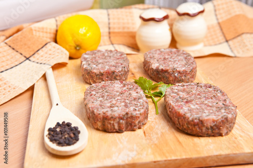 raw patties with spices on a cutting board