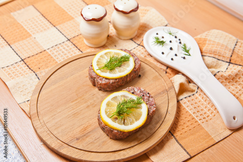 raw cutlets with lemon slices on a cutting board