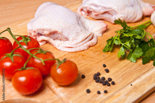 raw chicken legs with vegetables and spices on a cutting board