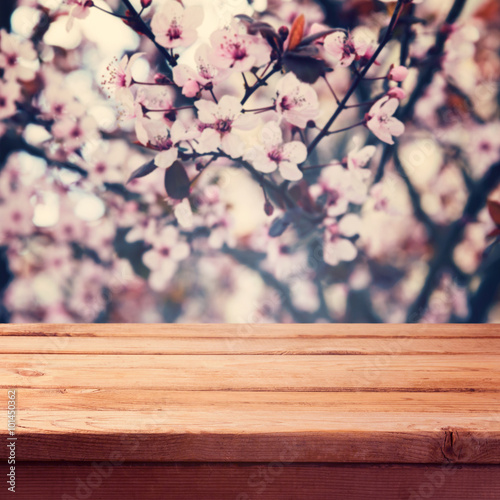 Empty wooden deck table over spring blossom flowers bokeh background