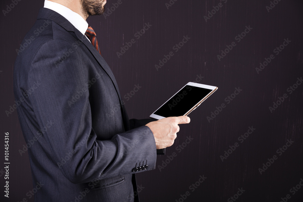Businessman holding a digital tablet against dark background Businessman holding a digital tablet against dark background