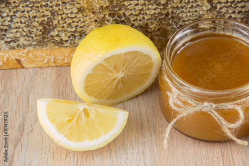 Golden honey in the comb in a jar and yellow sliced lemon