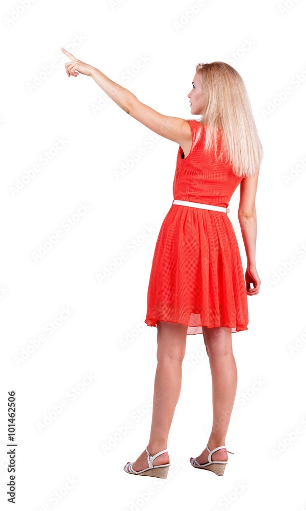 Back view of young blonde woman pointing at wall. Back view of young blonde woman pointing at wall.