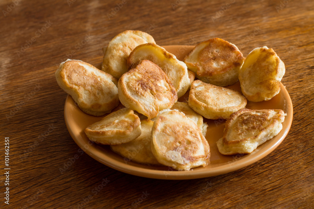 Heap of olady (traditional ukrainian pancakes) in orange plate on wood table. Heap of olady (traditional ukrainian pancakes) in orange plate on wood table.