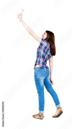 back view of standing young beautiful woman and using a mobile