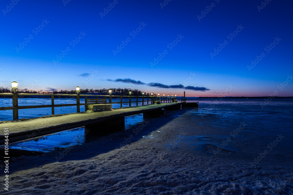 Jetty with lights during sunset a winter night