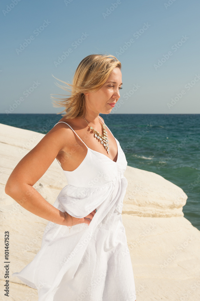 Young woman in white summer dress walking at the seaside Young woman in white summer dress walking at the seaside