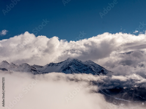 Alpine mountain peak emerging from a sea of clouds- 1